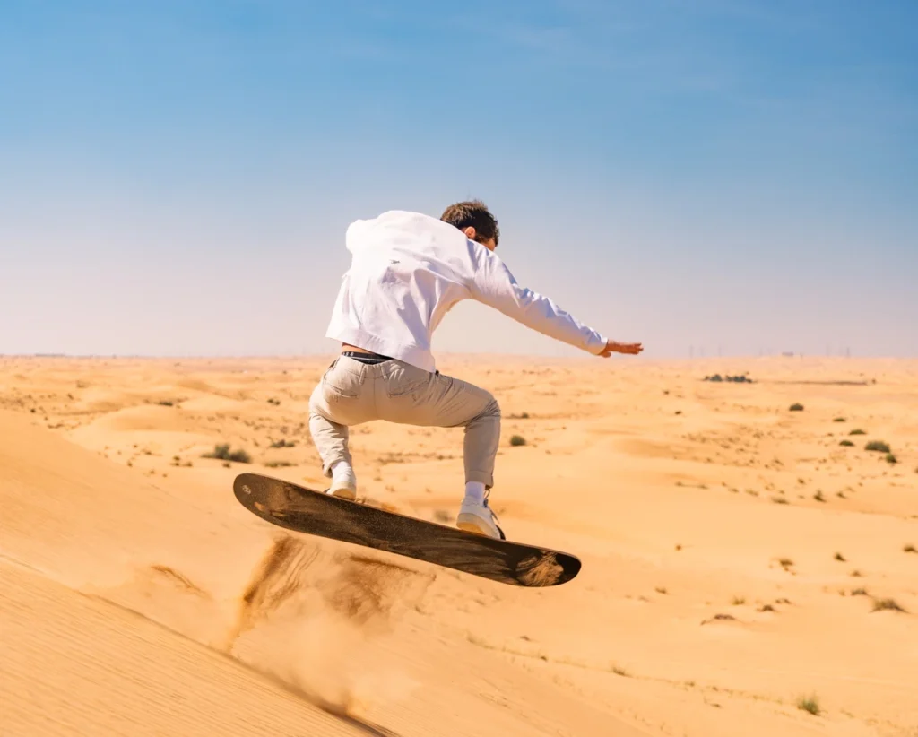 Customer sandboarding down the Dubai dunes in the desert during a tour with SAZ Dubai